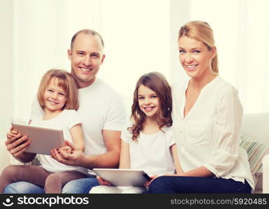 family, children, technology, money and home concept - smiling family and two little girls with tablet pc computers at home