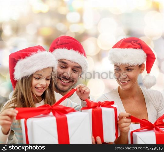 family, christmas, generation, holidays and people concept - happy family in santa helper hats with gift boxes over lights background