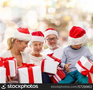 family, christmas, generation, holidays and people concept - happy family in santa helper hats with gift boxes sitting over lights background