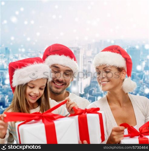 family, christmas, generation, holidays and people concept - happy family in santa helper hats with gift boxes over snowy city background