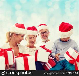 family, christmas, generation, holidays and people concept - happy family in santa helper hats with gift boxes sitting over blue lights background