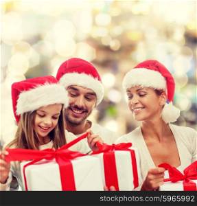 family, christmas, generation, holidays and people concept - happy family in santa helper hats with gift boxes sitting over lights background