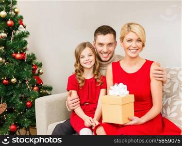 family, christmas, happiness and people concept - smiling family at home with gift box