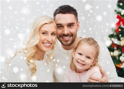 family, christmas, holidays and people concept - happy mother, father and little daughter sitting on sofa at home