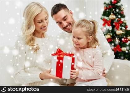 family, christmas, holidays and people concept - happy mother, father and little daughter with gift box sitting on sofa at home