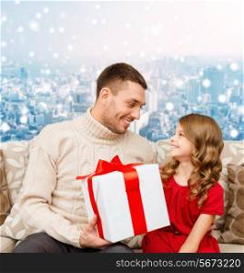 family, christmas, holidays and people concept -smiling father and daughter with gift box over snowy city background