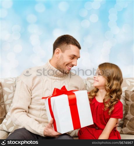 family, christmas, holidays and people concept -smiling father and daughter with gift box over blue lights background