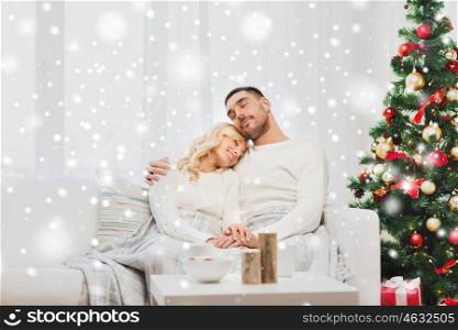 family, christmas, holidays, love and people concept - happy couple covered with plaid sitting on sofa at home