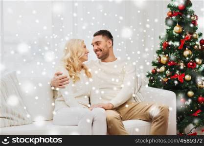 family, christmas, holidays, love and people concept - happy couple sitting on sofa at home