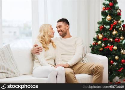 family, christmas, holidays, love and people concept - happy couple sitting on sofa at home