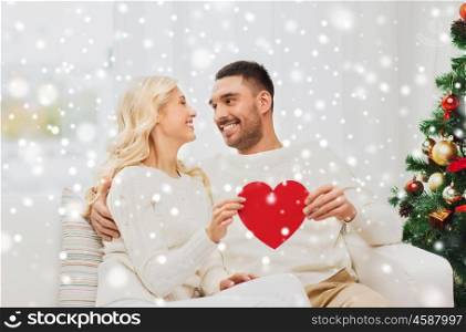 family, christmas, holidays, love and people concept - happy couple with red heart at home