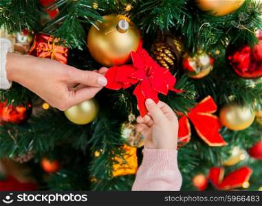 family, christmas, holidays, new year and people concept - close up of mother and child hands decorating christmas tree