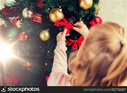 family, christmas, holidays, new year and people concept - close up of child decorating christmas tree. close up of child decorating christmas tree