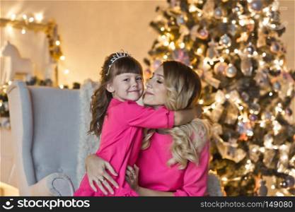 Family Christmas portrait by the fireplace and ate decorated with garlands of lights.. Portrait of a mother and daughter from the fireplace and Christmas tree 9