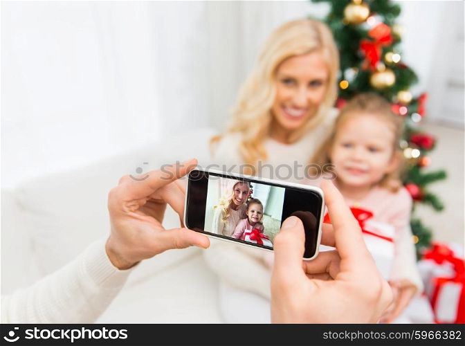 family, christmas, technology and people concept - close up of man taking picture of his family by smatrphone