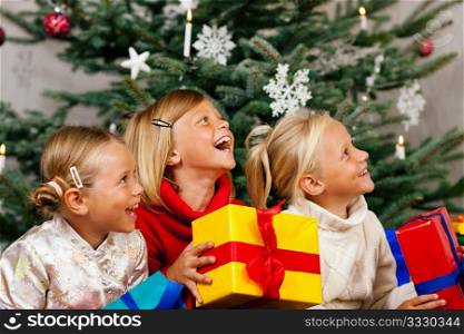 Family Christmas - three children having received gifts showing them around