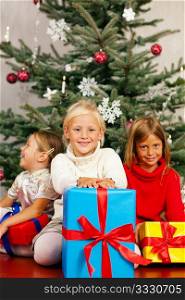 Family Christmas - three children having received gifts showing them around