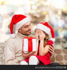 family, christmas, winter holidays and people concept - smiling daughter with closed eyes waiting for present from father over lights background