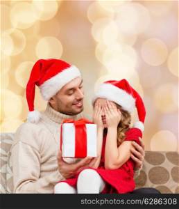 family, christmas, winter holidays and people concept - smiling daughter with closed eyes waiting for present from father over beige lights background