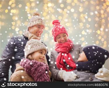 family, christmas, winter, season and people concept - happy family outdoors over holidays lights background and snow