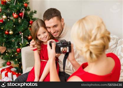 family, christmas, x-mas, happiness and people concept - mother taking picture of smiling father and daughter