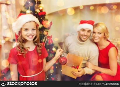 family, christmas, x-mas, happiness and people concept - smiling family in santa helper hats decorating christmas tree