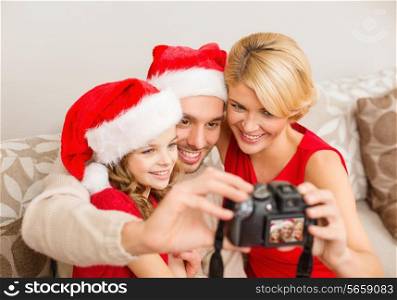 family, christmas, x-mas, happiness and people concept - smiling family in santa helper hats taking picture with photo camera