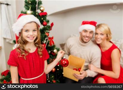 family, christmas, x-mas, happiness and people concept - smiling family in santa helper hats decorating christmas tree