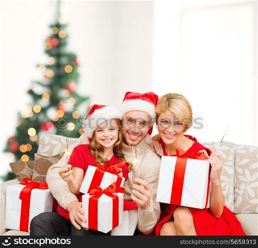 family, christmas, x-mas, happiness and people concept - smiling family in santa helper hats with many gift boxes and bengal lights