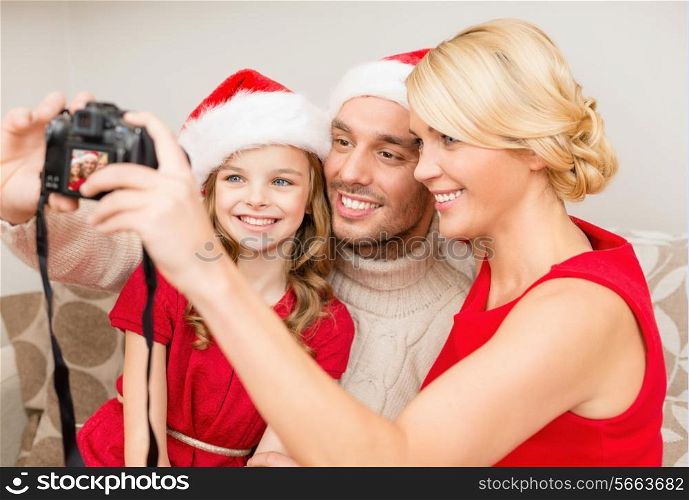 family, christmas, x-mas, happiness and people concept - smiling family in santa helper hats taking picture with photo camera