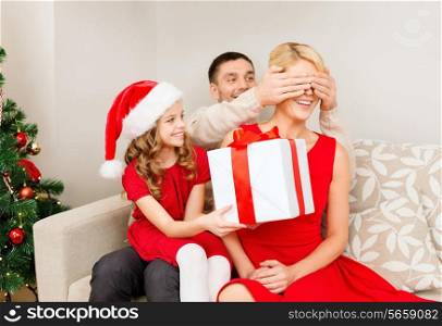 family, christmas, x-mas, happiness and people concept - smiling father and daughter surprise mother with big gift box