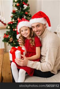 family, christmas, x-mas, happiness and people concept - smiling father and daughter in santa helper hats holding gift box