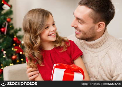 family, christmas, x-mas, happiness and people concept - smiling father and daughter holding gift box and looking at each other