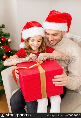 family, christmas, x-mas, happiness and people concept - smiling father and daughter in santa helper hats opening gift box