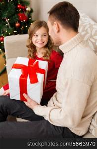 family, christmas, x-mas, happiness and people concept - smiling father and daughter holding gift box and looking at each other