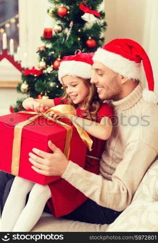 family, christmas, x-mas, happiness and people concept - smiling father and daughter in santa helper hats opening gift box