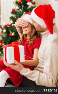 family, christmas, x-mas, happiness and people concept - smiling father surprise daughter with gift box covering eyes with hand