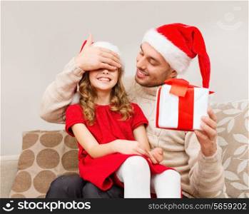 family, christmas, x-mas, happiness and people concept - smiling father surprise daughter with gift box covering eyes with hand