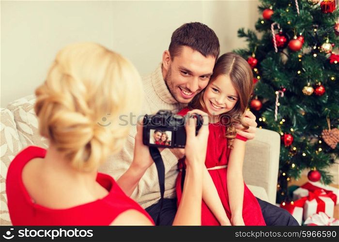 family, christmas, x-mas, winter, happiness and people concept - mother taking picture of smiling father and daughter