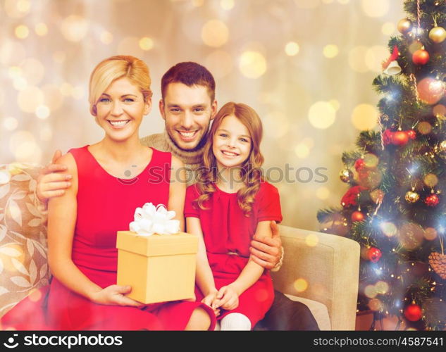 family, christmas, x-mas, winter, happiness and people concept - smiling family at home with gift box