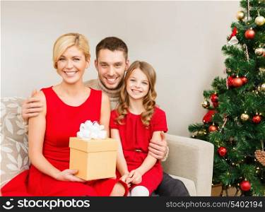 family, christmas, x-mas, winter, happiness and people concept - smiling family at home with gift box