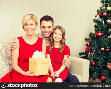 family, christmas, x-mas, winter, happiness and people concept - smiling family at home with gift box