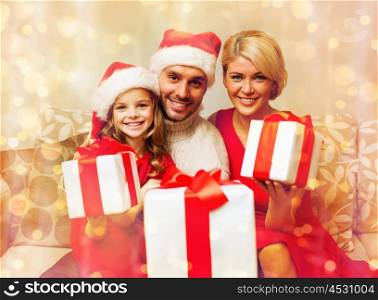 family, christmas, x-mas, winter, happiness and people concept - smiling family in santa helper hats with many gift boxes. smiling family giving many gift boxes