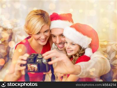 family, christmas, x-mas, winter, happiness and people concept - smiling family in santa helper hats taking picture with photo camera