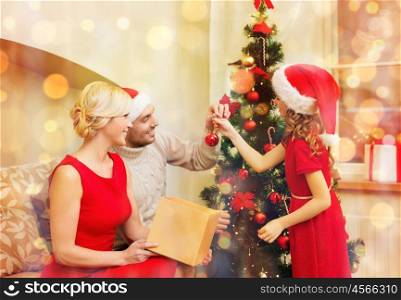 family, christmas, x-mas, winter, happiness and people concept - smiling family in santa helper hats decorating christmas tree