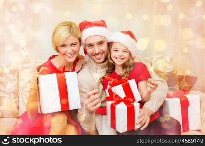 family, christmas, x-mas, winter, happiness and people concept - smiling family in santa helper hats with many gift boxes and bengal lights