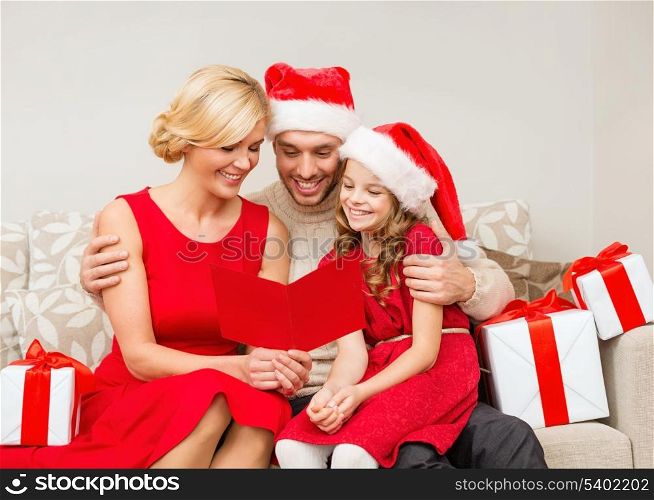family, christmas, x-mas, winter, happiness and people concept - smiling family in santa helper hats with many gift boxes reading postcard