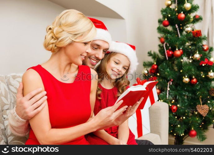 family, christmas, x-mas, winter, happiness and people concept - smiling family in santa helper hats with many gift boxes reading book