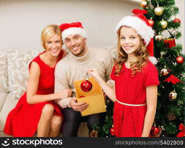 family, christmas, x-mas, winter, happiness and people concept - smiling family in santa helper hats decorating christmas tree