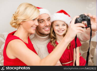 family, christmas, x-mas, winter, happiness and people concept - smiling family in santa helper hats taking picture with photo camera